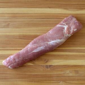 A close up shot of a cleaned pork loin on a wooden cutting board