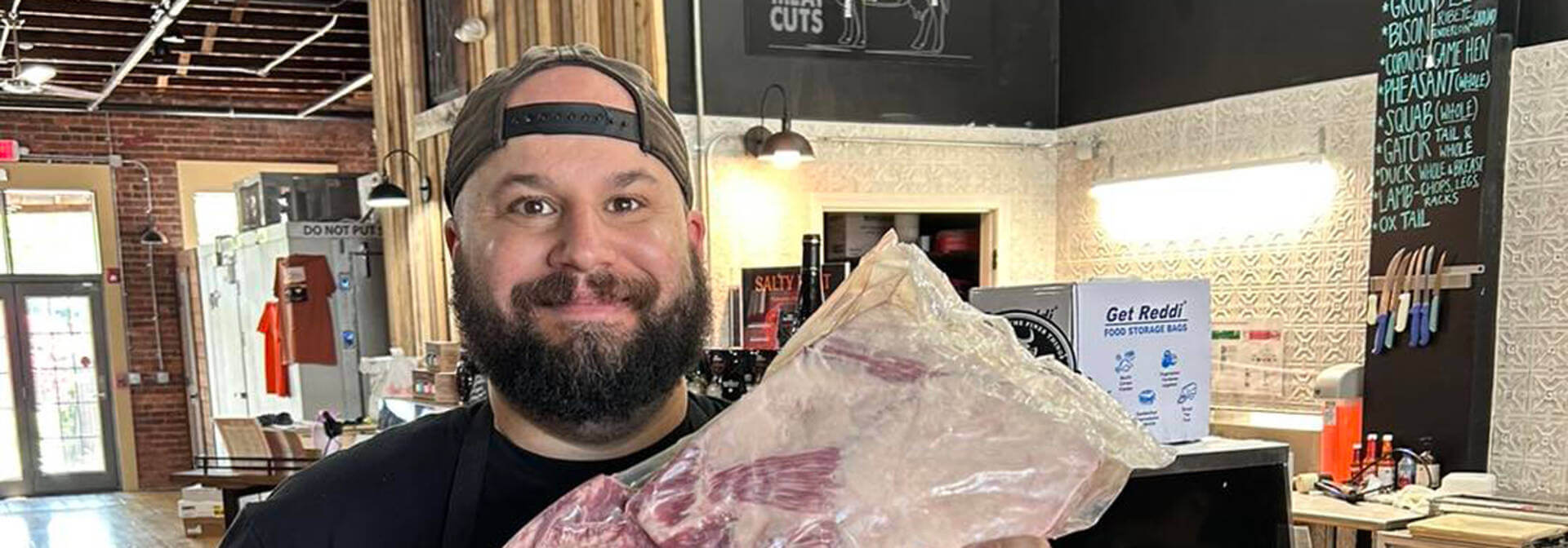 The Stock & Barrel butcher holding a cut of meat