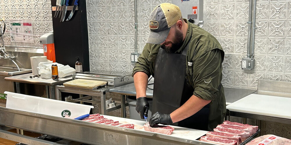 The butcher at Stock & Barrel trimming cuts of meat in the clean processing area